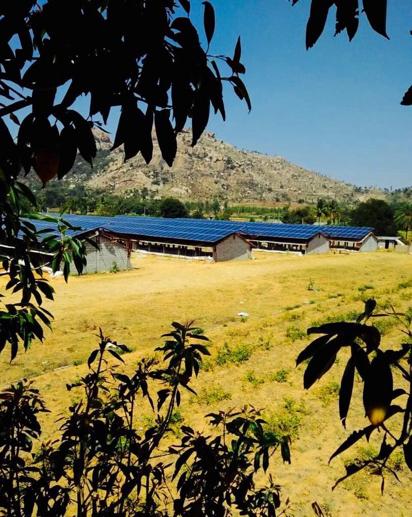 Rooftop solar over industrial sheds with scenic hill backdrop — India
